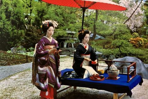 Staged image showing two geishas performing a tea ceremony in a garden