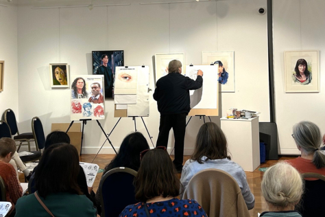 Artist doing painting demonstration in gallery for audience